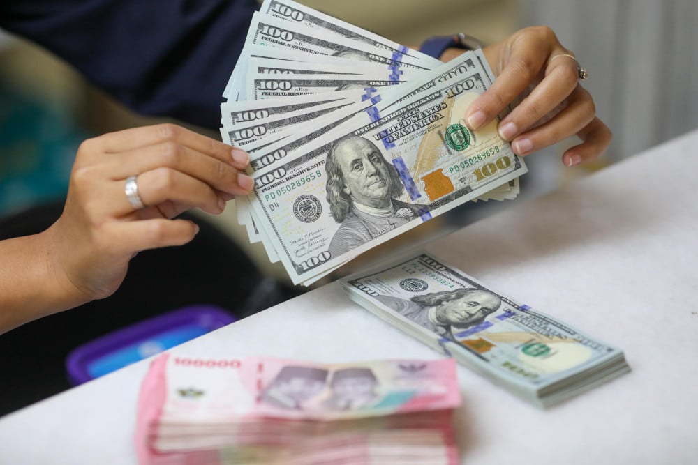 Pegawai menunjukan mata uang dolar Amerika Serikat (AS) dan rupiah di gerai penukaran uang atau money changer Ayu Masagung, Jakarta, Selasa (5/5/2026). Bisnis/Himawan L. Nugraha