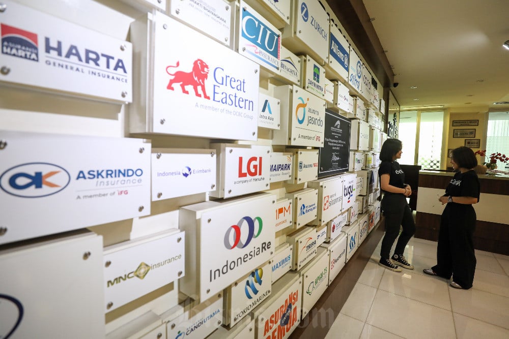 Karyawati beraktivitas di dekat logo-logo perusahaan asuransi umum di Jakarta, Rabu (24/7/2024). Bisnis/Arief Hermawan P