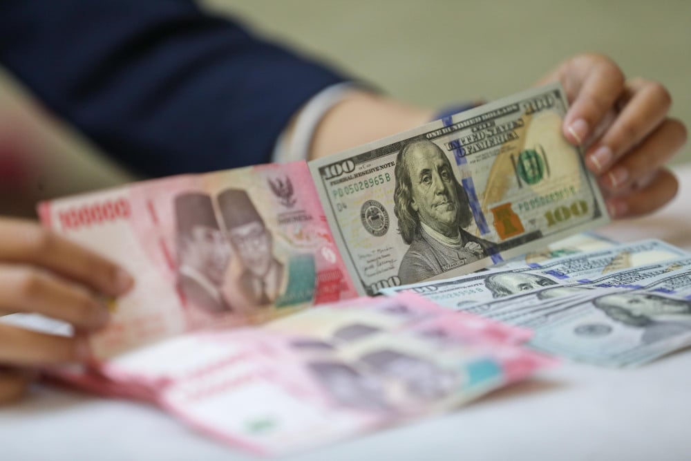 Pegawai menunjukan mata uang dolar Amerika Serikat (AS) dan rupiah di gerai penukaran uang atau money changer Ayu Masagung, Jakarta, Selasa (5/5/2026). Bisnis/Himawan L. Nugraha
