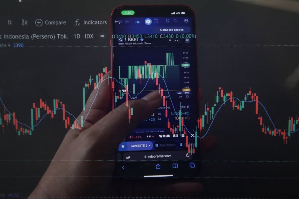 Warga mencari informasi harga saham di Jakarta, Minggu (19/4/2026). JIBI/Bisnis/Fanny Kusumawardhani