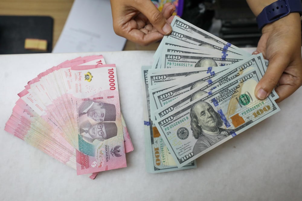 Pegawai menunjukan mata uang dolar Amerika Serikat (AS) dan rupiah di gerai penukaran uang atau money changer Ayu Masagung, Jakarta, Selasa (5/5/2026). Bisnis/Himawan L. Nugraha