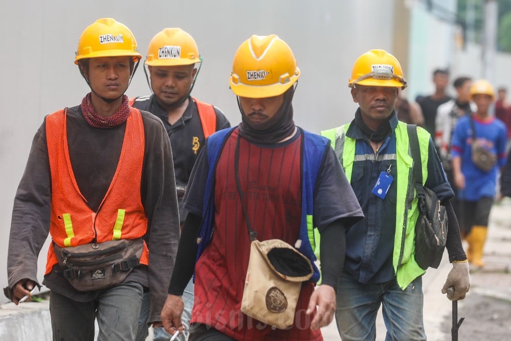 Pekerjaan melintas di dekat proyek pembangunan gedung bertingkat di Jakarta, Selasa (11/11/2025). Bisnis/Abdurachman