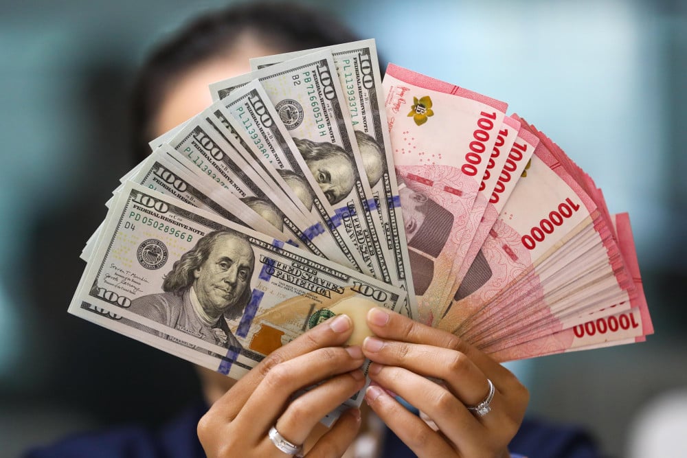 Pegawai menunjukan mata uang dolar Amerika Serikat (AS) dan rupiah di gerai penukaran uang atau money changer Ayu Masagung, Jakarta, Selasa (5/5/2026). Bisnis/Himawan L. Nugraha