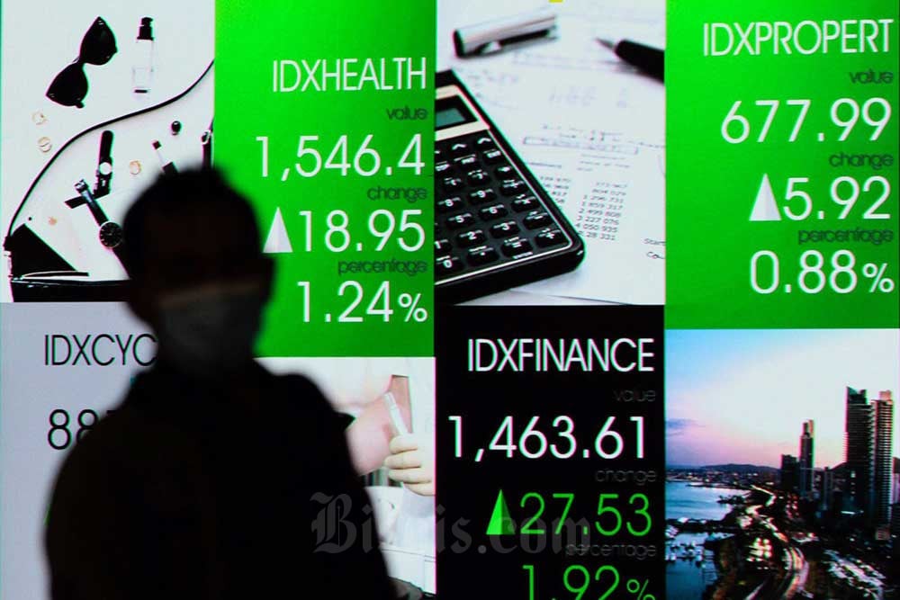 Karyawan melintas di dekat layar pergerakan indeks harga saham gabungan (IHSG) di Bursa Efek Indonesia, Jakarta, Rabu (20/7/2022). Bisnis/Fanny Kusumawardhani