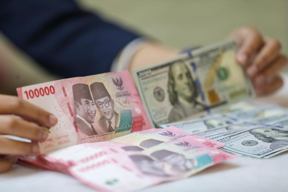 Pegawai menunjukan mata uang dolar Amerika Serikat (AS) dan rupiah di gerai penukaran uang atau money changer Ayu Masagung, Jakarta, Selasa (5/5/2026). Bisnis/Himawan L. Nugraha