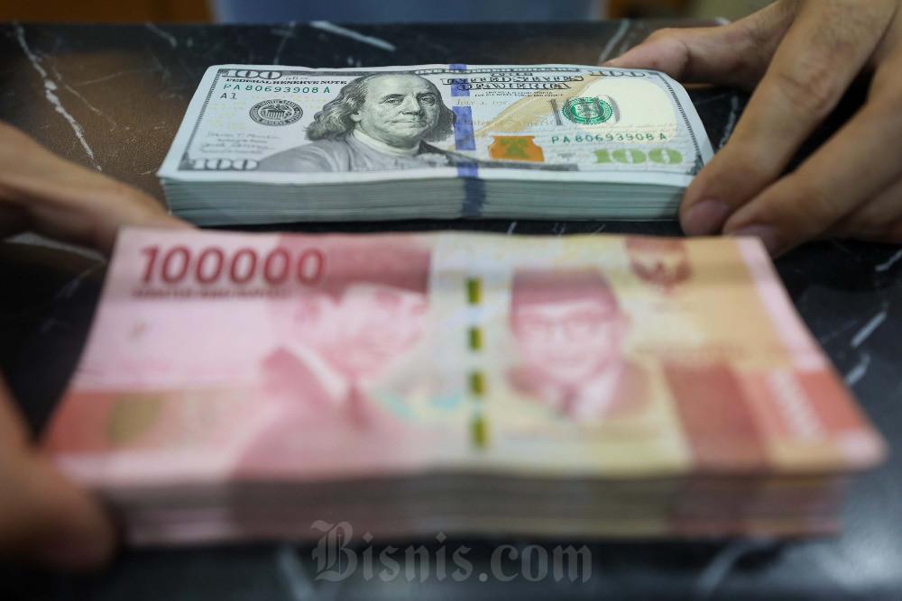 Pegawai menunjukan mata uang dolar Amerika Serikat (AS) dan rupiah di Jakarta, Senin (16/6/2025). Bisnis/Himawan L Nugraha