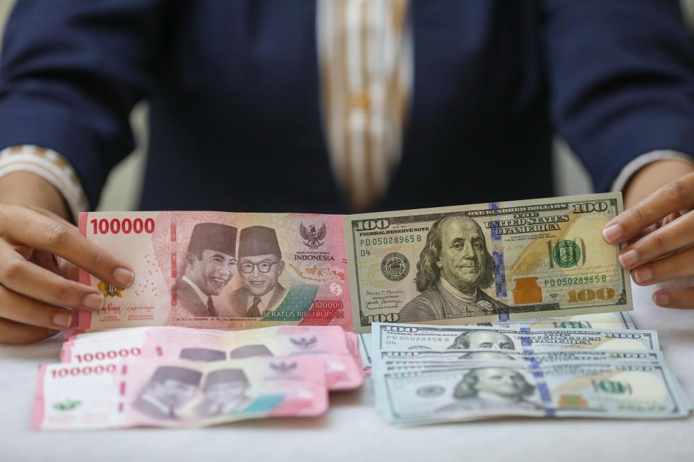 Pegawai menunjukan mata uang dolar Amerika Serikat (AS) dan rupiah di gerai penukaran uang atau money changer Ayu Masagung, Jakarta, Selasa (5/5/2026). Bisnis/Himawan L. Nugraha