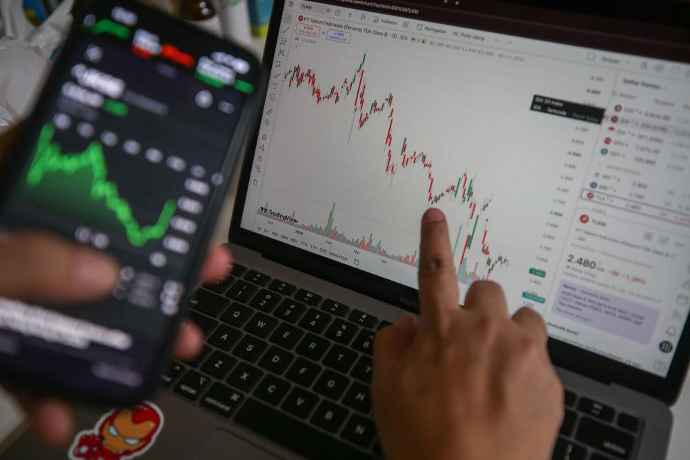 Investor mengamati data saham menggunakan gawai di Jakarta, Minggu (12/7/2026). Bisnis/Himawan L. Nugraha