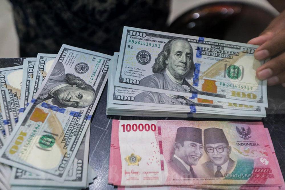Pegawai menunjukan mata uang Dolar Amerika Serikat dan Rupiah di Money Changer, Jakarta, Senin (6/7/2026). Bisnis/Himawan L Nugraha