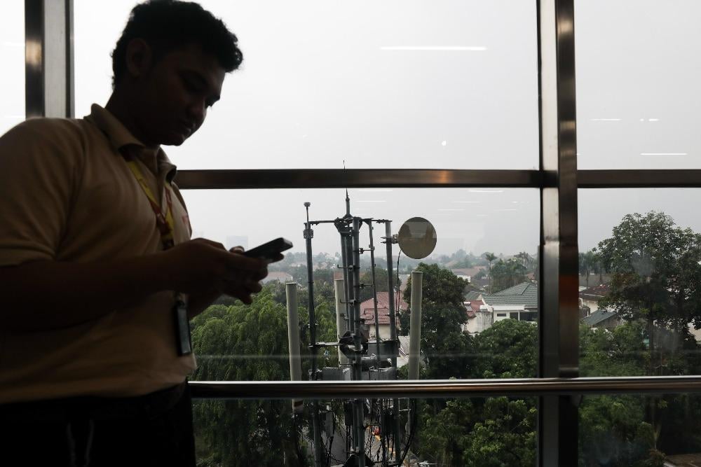 Pekerja membuka internet dari smartphone di dekat BTS 5G