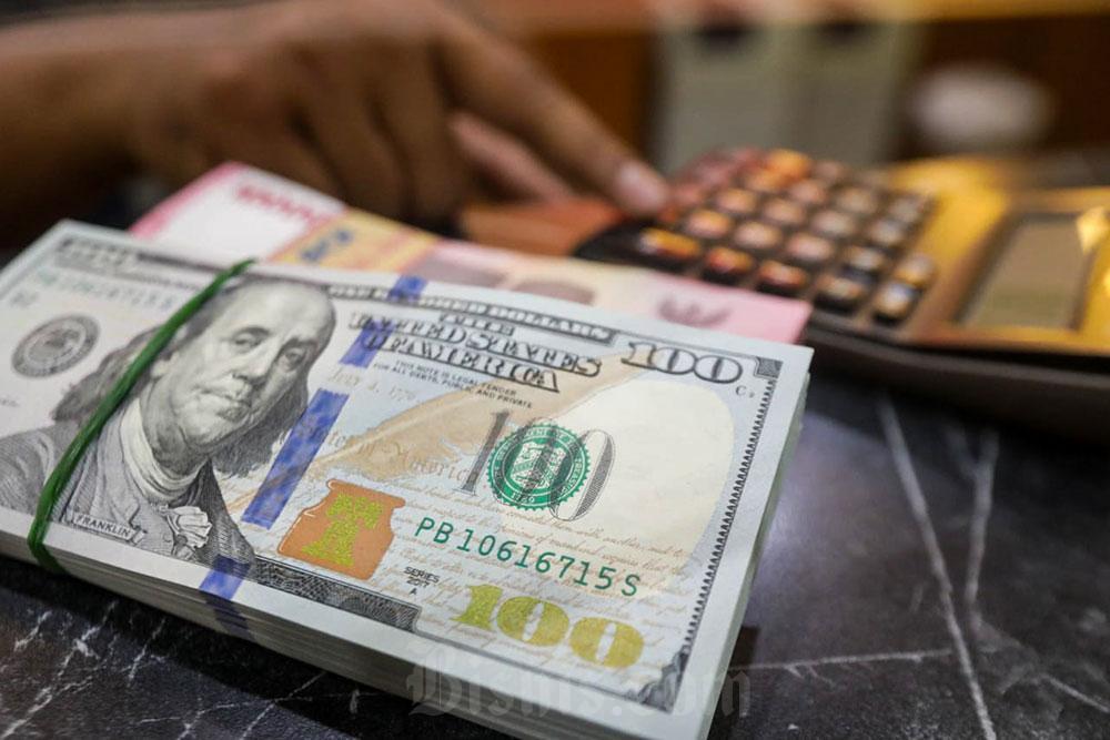 Pegawai menunjukan mata uang Dolar Amerika Serikat dan Rupiah di Money Changer, Jakarta, Senin (6/7/2026). Bisnis/Himawan L Nugraha