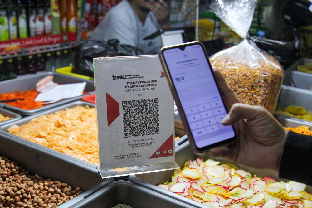 Pembeli membayar dengan menggunakan QRIS di Pasar Santa, Jakarta, Sabtu (11/4/2026). Bisnis/Robby Fathan