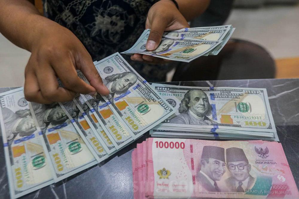 Pegawai menunjukan mata uang Dolar Amerika Serikat dan Rupiah di Money Changer, Jakarta, Senin (6/7/2026). Bisnis/Himawan L Nugraha